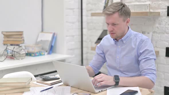 Businessman Feeling Defeated While Working on Laptop