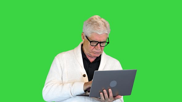 Happy Senior Holding a Laptop and Typing on a Green Screen, Chroma Key