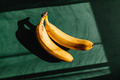 Bananas on a green background. Summer abstract creative photography with sun light and shadows. - PhotoDune Item for Sale