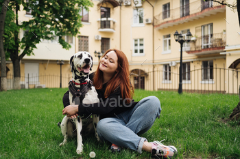 Pretty woman posing and hugging dalmatian dog on street city background / Photodune, Misc