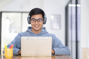 Young collage student using computer and mobile device studying online. / Photodune, Misc