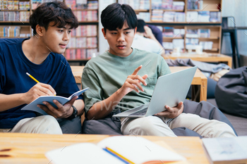 n and man studying for a test or an exam. Tutor books with friends. Young students campus helps friend catching up and learning.