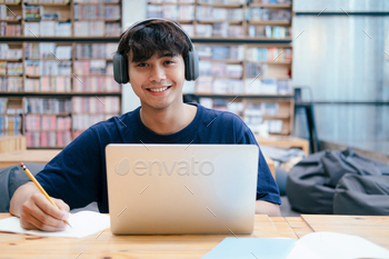 Young collage student using computer and mobile device studying online. / Photodune, Misc