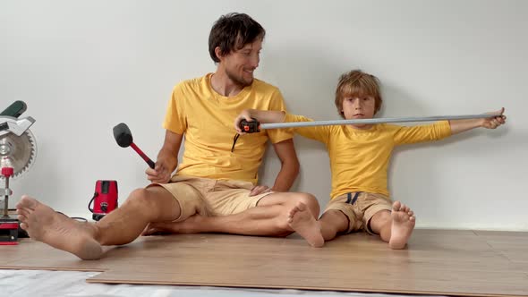 Father and His Little Son Install Laminate on the Floor in Their Apartment