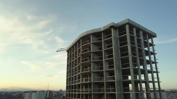 Aerial view of concrete frame of tall unfinished apartment building under construction in a city