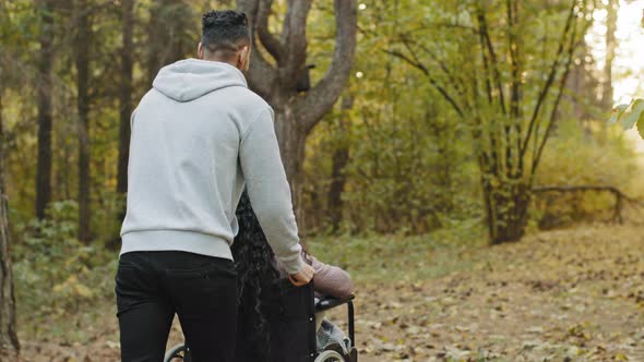 View From Back Boyfriend Walking Girlfriend with in Wheelchair in Hospital Park Visiting Patient