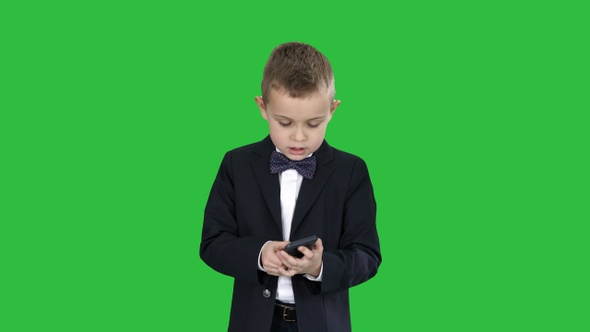 Small boy in costume walking and using smartphone 