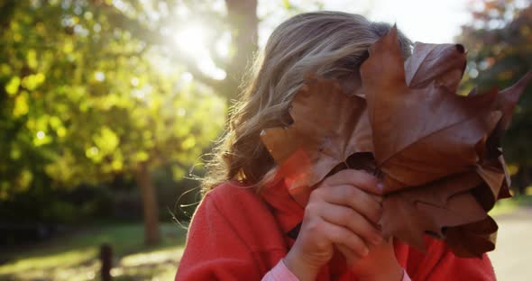 Girl hiding smile behind leaf