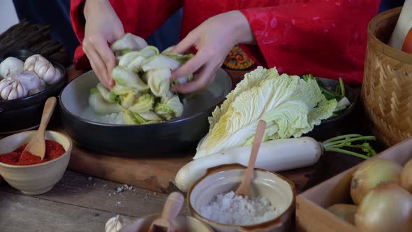 Asian women wearing Korean traditional costumes (hanbok) are Sprinkling salt by hand and Kimchi ingr