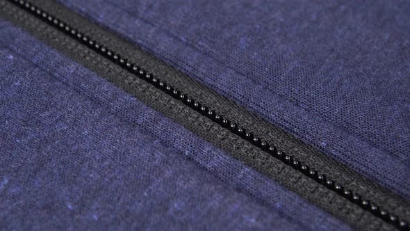 hand fastens a black plastic zipper lock on a blue sports jacket. 