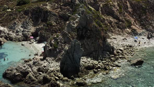 Dolly out aerial shot of a narrow beach on the Italian Mediterranean Sardinia Island