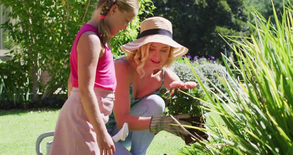 Caucasian mother and daughter taking care of plants outdoors