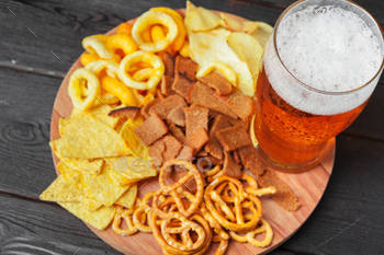 Lager beer and snacks on wooden table. Nuts, chips, pretzel / Photodune, Misc