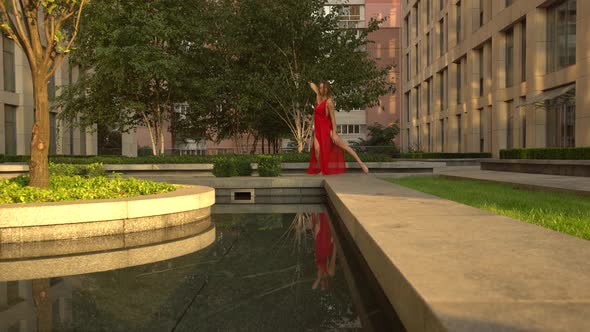 Beautiful Young Girl Dancing on the Street of a Modern City and Is Reflected in the Water