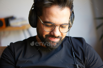 Handsome bearded man in headphones listening to music at home. Relaxing and rest time concept. / Photodune, Misc