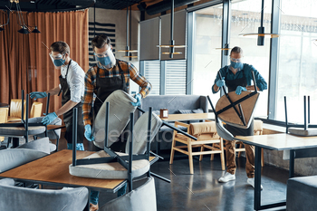 Three male waiters in protective workwear arranging furniture in restaurant / Photodune, Misc