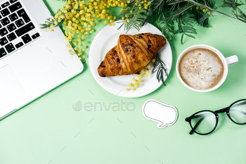 Woman work space with laptop, mimosa flower, croissant, coffee and stationery / Photodune, Misc