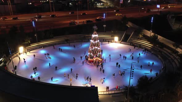 People Skate on the Rink Around New Year's Tree