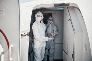 Flight attendants in protective suits welcoming passengers / Photodune, Misc