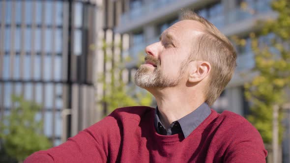 A Middleaged Handsome Caucasian Man Looks Around As He Sits in a Street in an Urban Area