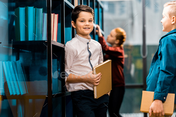 cute smiling schoolchildren holding books while studying in library / Photodune, Misc