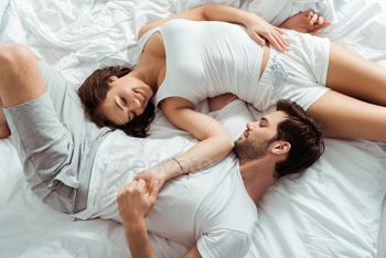 top view of beautiful girl looking at man and holding hands while lying on bed / Photodune, Misc