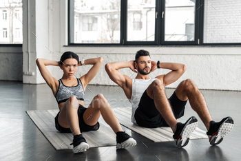 sporty young couple doing abs exercise on yoga mats in gym / Photodune, Misc