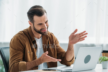 handsome and happy man smiling and looking at screen of laptop / Photodune, Misc