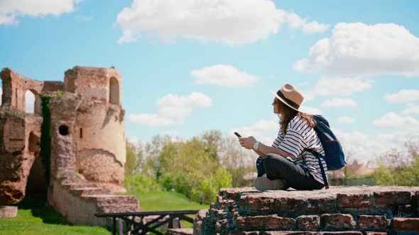 A Young Woman Using Her Smartphone While Sitting at the Historical Fortress