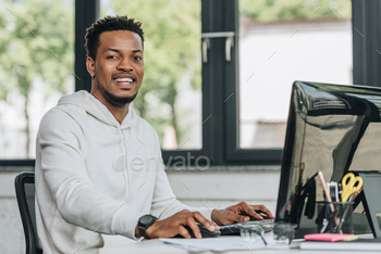 cheerful african american programmer looking at camera while working on computer in office / Photodune, Misc