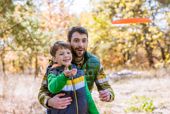 Smiling father and cute little son playing with frisbee and having fun in autumn park / Photodune, Misc