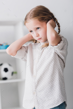 close-up portrait of depressed little kid covering ears with hands and looking away / Photodune, Misc