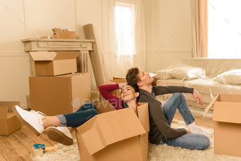 tired couple sitting in cardbox and on floor at new home / Photodune, Misc