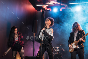 Young multiethnic rock and roll band performing hard rock music on stage / Photodune, Misc