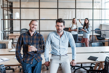 handsome young businessman sitting and smiling at camera in office / Photodune, Misc