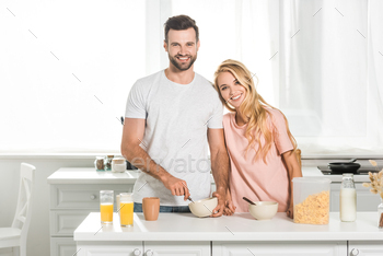 happy couple with bowls of cereal during breakfast at kitchen / Photodune, Misc