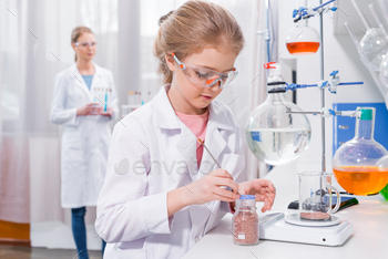 Little girl in white coat making experiment in chemical lab / Photodune, Misc