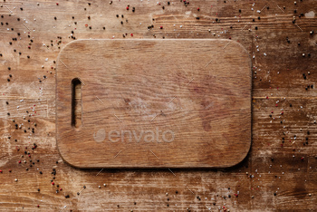 top view of cutting board on wooden table with scattered peppercorns / Photodune, Misc