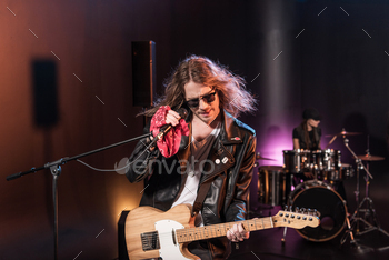 Male singer with microphone and rock and roll band performing hard rock music on stage / Photodune, Misc
