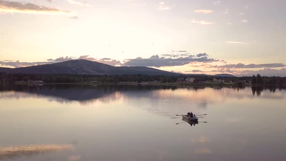 Group of friends rowing a boat in a calm lake during midnight sun in Lapland.