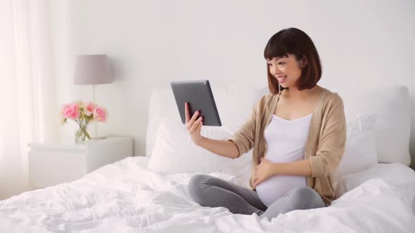 Happy Pregnant Asian Woman with Tablet Pc at Home