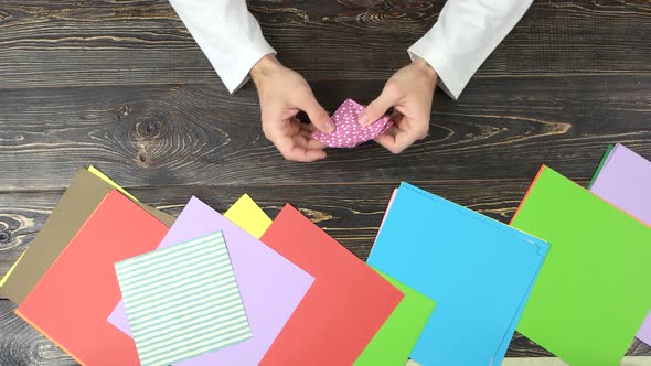 Man Folding Origami From Pink Paper