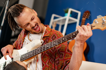Young man guitar player sitting and performing on a couch / Photodune, Misc