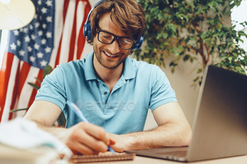 Young bearded businessman sitting at table with laptop and american flag / Photodune, Misc