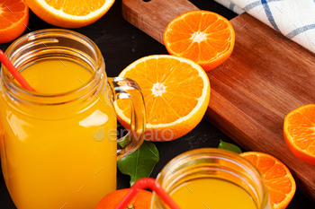 Glass of orange juice and cut oranges on table / Photodune, Misc