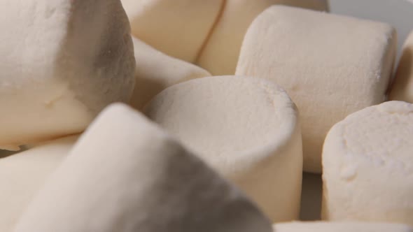 Numerous Fluffy White Marshmallows Rotating on a Surface