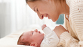 Closeup portrait of smiling loving mother stroking and looking on her newborn baby son lying on bed - PhotoDune Item for Sale