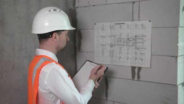 Work with the drawings of a civil engineer at a construction site. The construction foreman is worki