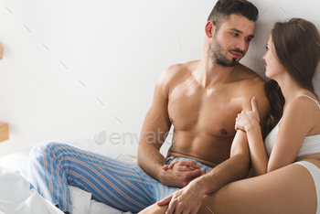 young couple sitting in bed in morning and holding hands / Photodune, Misc