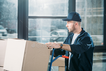 Loader man adjusting cardboard boxes on cart / Photodune, Misc